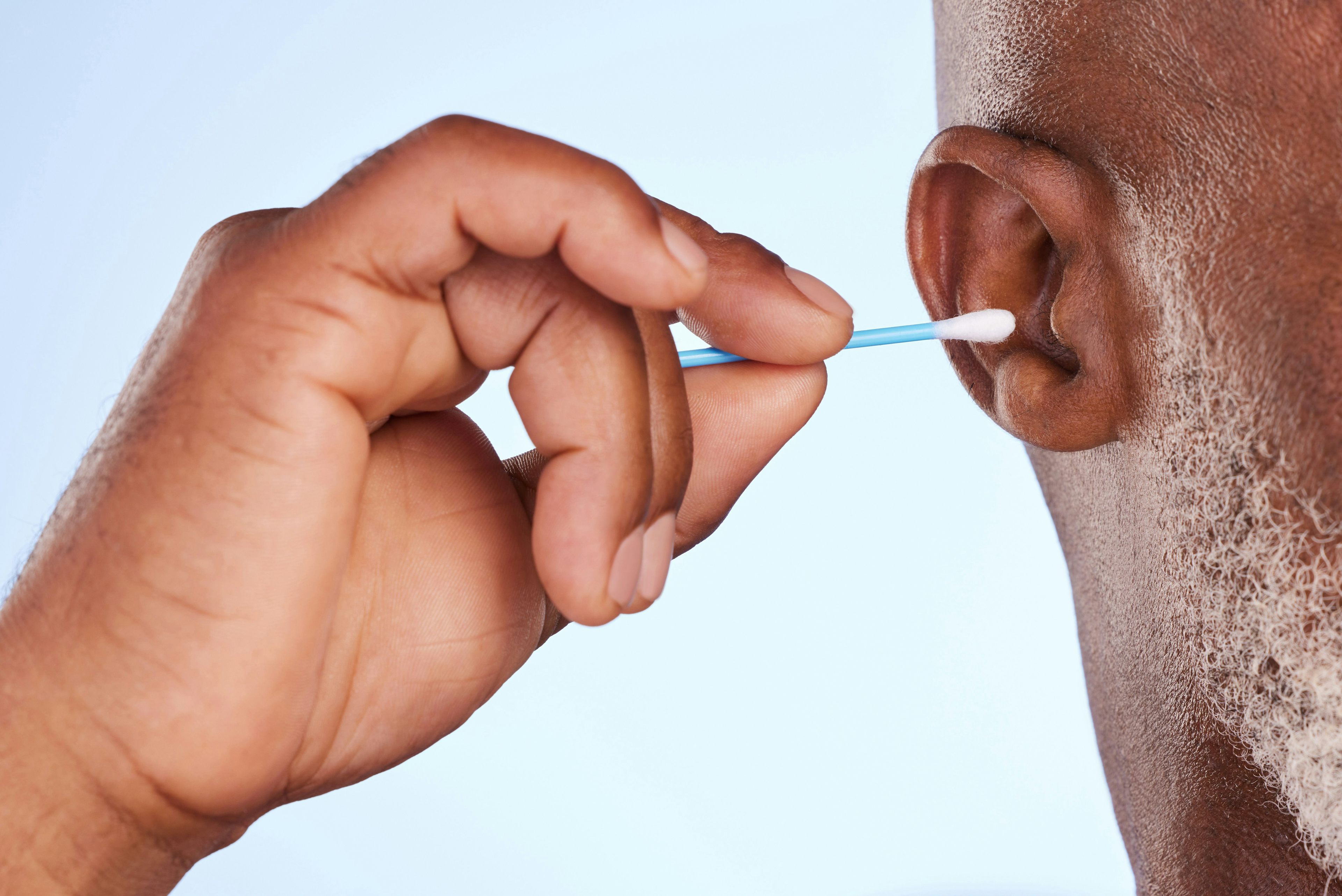 Ein Mann versucht, den Ohrenschmalz mit Wattestäbchen zu entfernen.