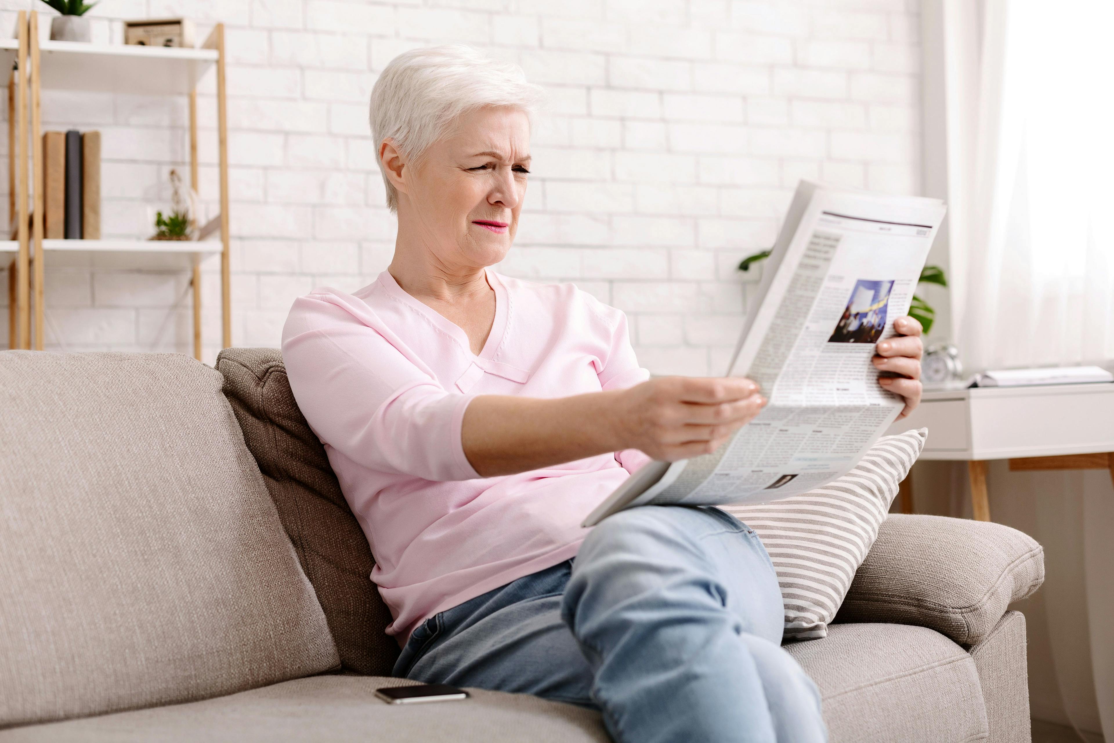 Eine Seniorin mit Astigmatismus liest die Zeitung 