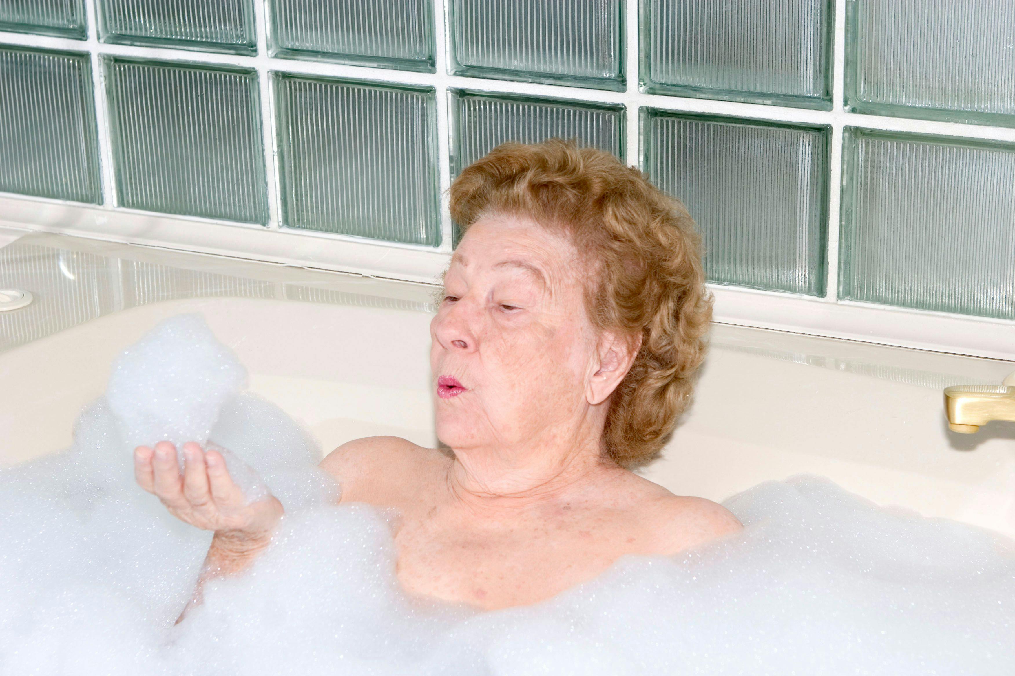 Eine Seniorin badet - ein Badewannenlift hilft ihr dabei